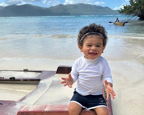 Fernando happily sitting on a sandy beach.