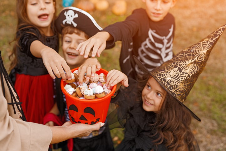Group of children reaching in for Halloween treats.