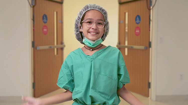 recovered patient Maja, in surgical scrubs as she tours the hospital.
