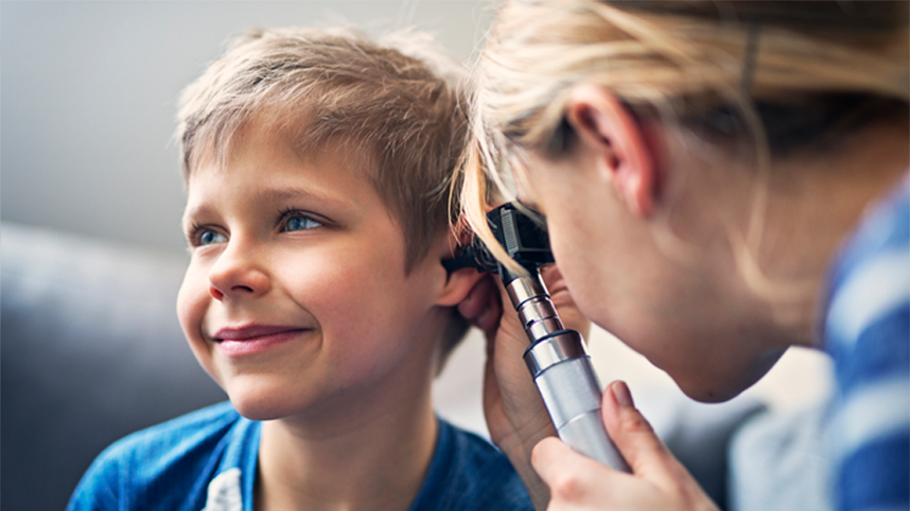 boy receiving ear exam with otoscope.