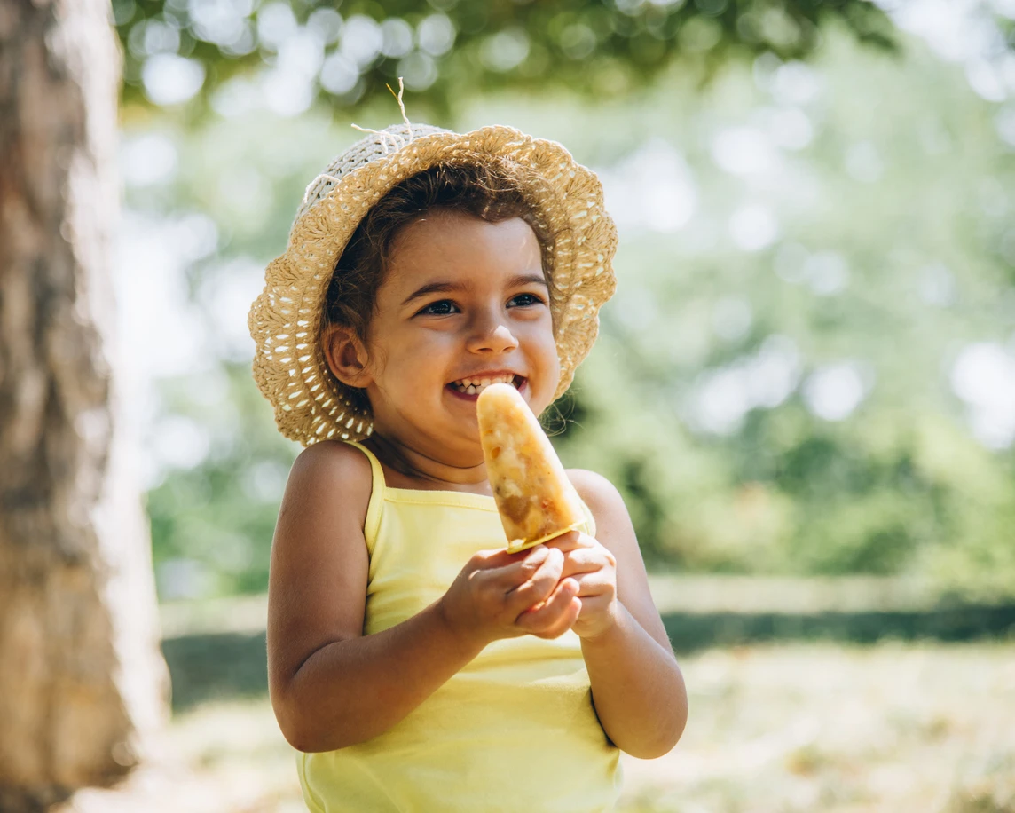 Young girl enjoying frozen fruit popsicle.