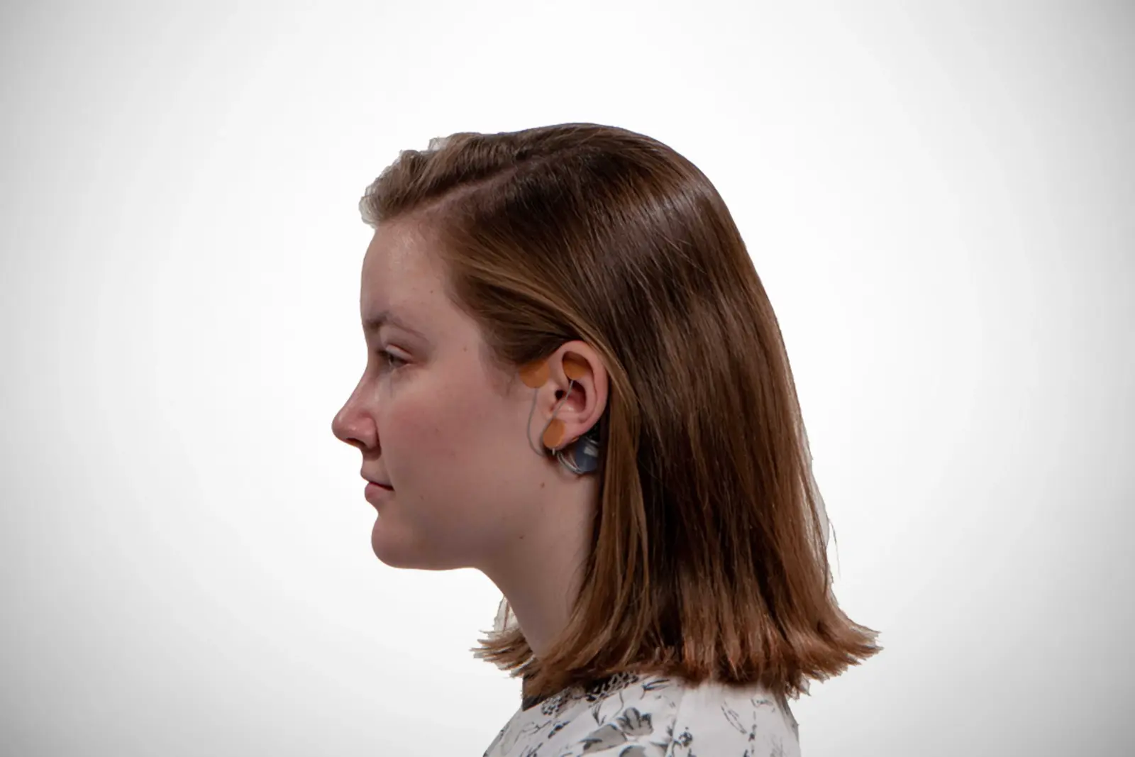 Foto de perfil de una niña joven con el dispositivo ib-stim en su oreja.
