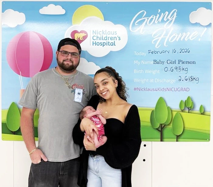 la pequeña bebé Pierson sostenida por su madre y padre el día de salida del hospital.