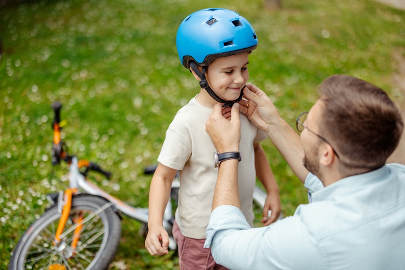 Dad putting helmet on son before riding bike.