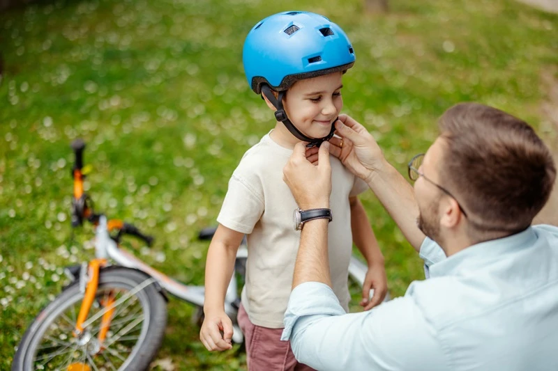Papá poniéndole el casco a su hijo antes de montar en bicicleta.