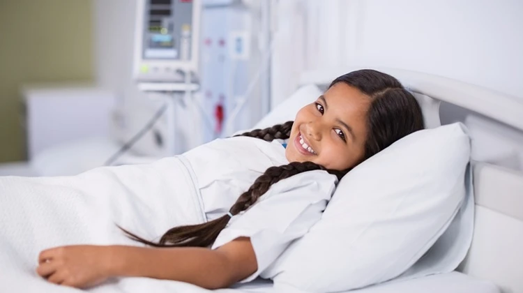 girl smiling in hospital bed.