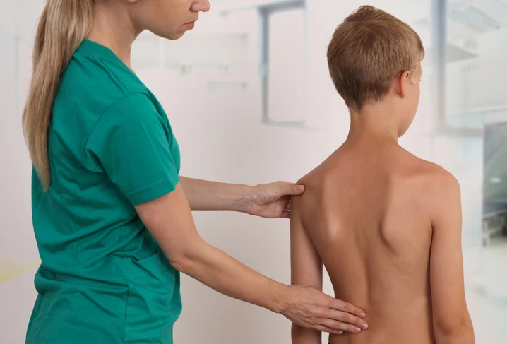 Female nurse examining boy's spine.