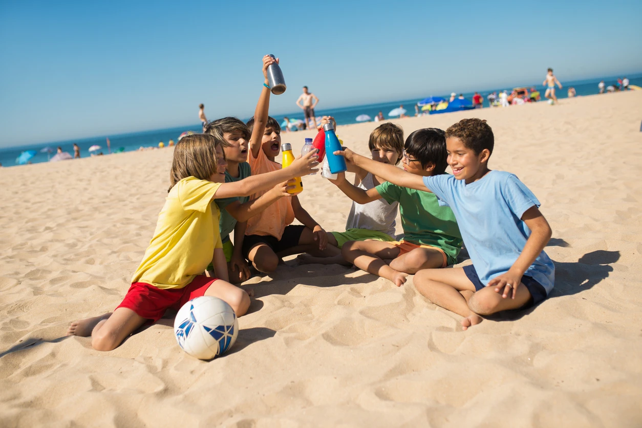 Group of boys drinking water on the beach.