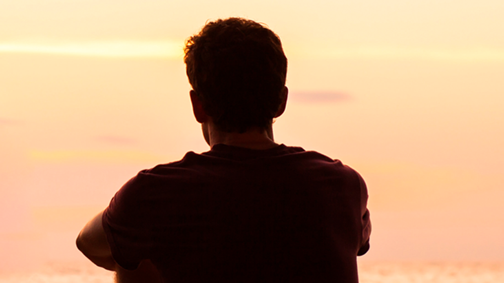 teenage boy looking at sunset.