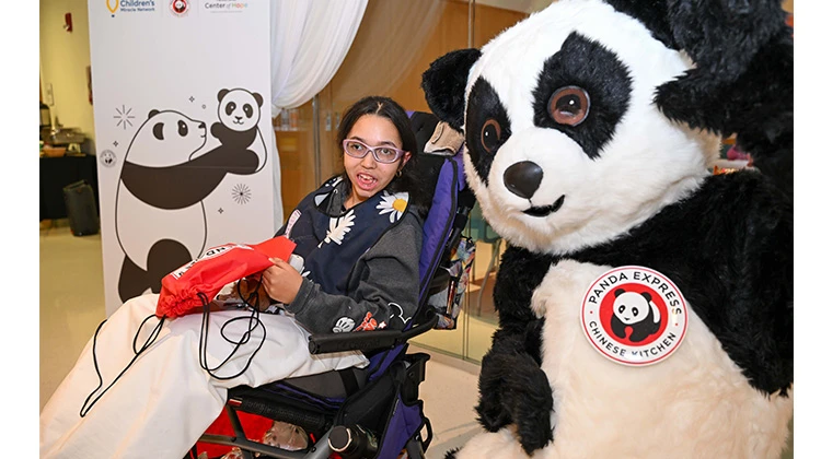 group of volunteers and panda character mascot at a table with goodies.