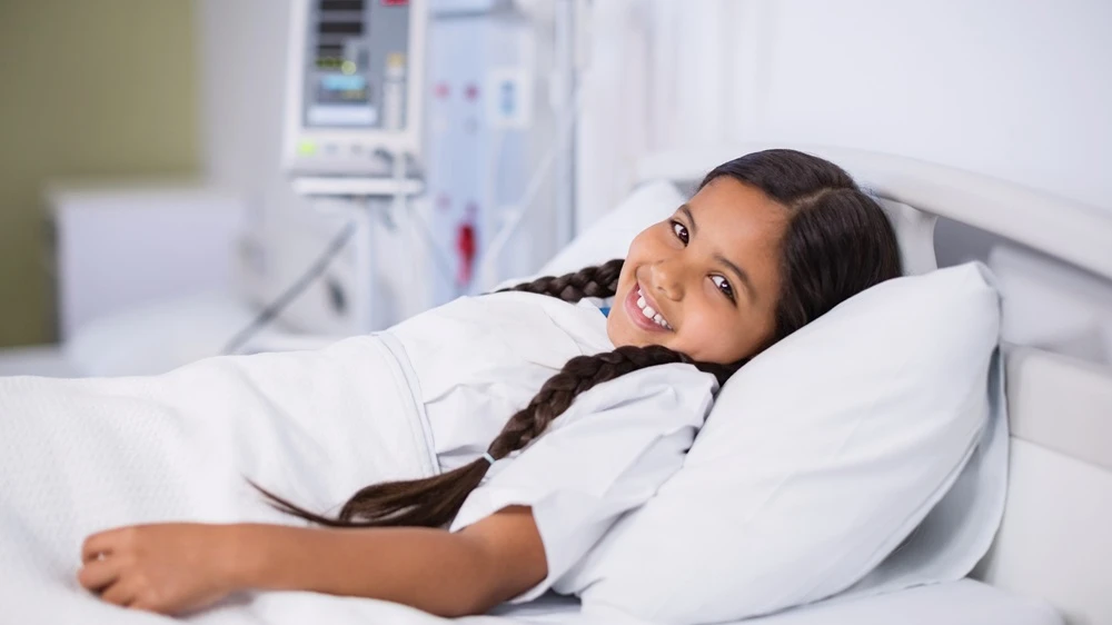 girl smiling in hospital bed.