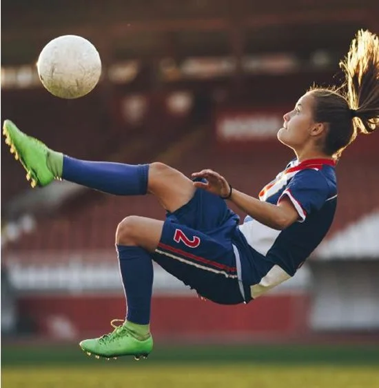 soccer player kicking ball in midair.