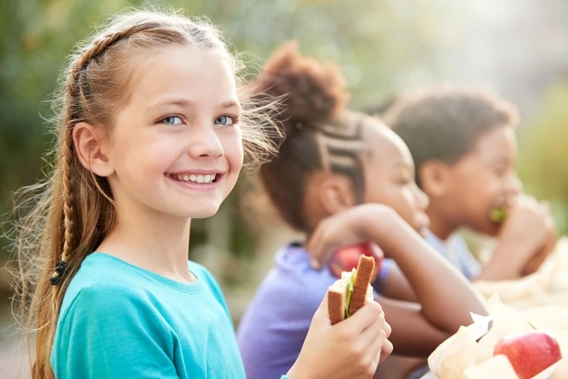 girl smiling at camera, eating.