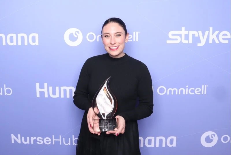 Dr. Sarik wearing black holding glass award.
