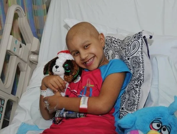 patient veronica hugs a puppy stuffed animal at her hospital bed.