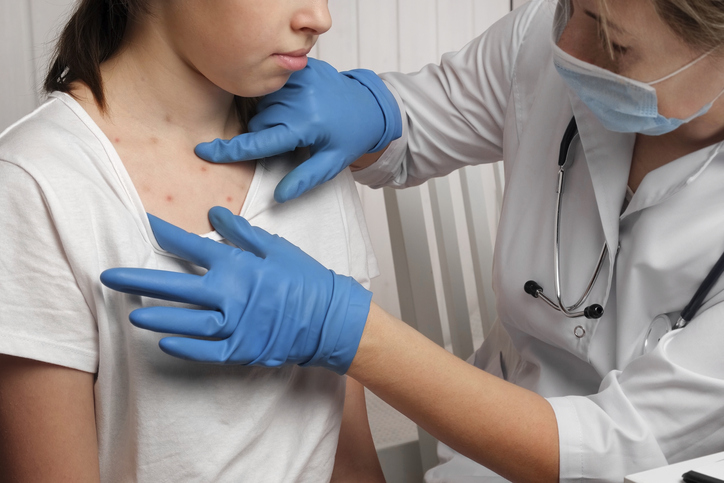Female doctor examining female patient for measles.
