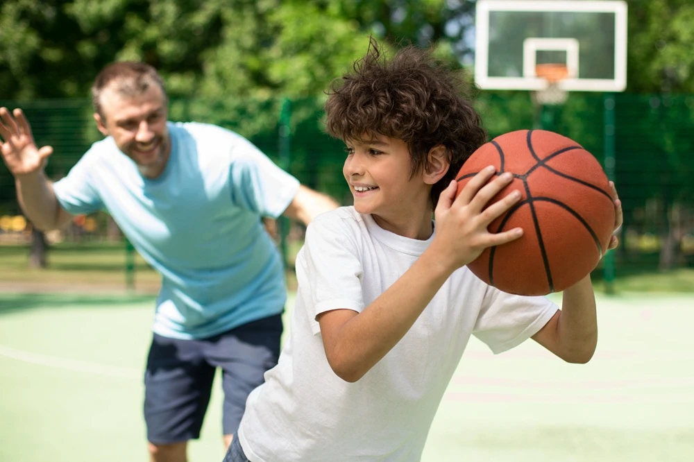 Dad playing basketball with son.