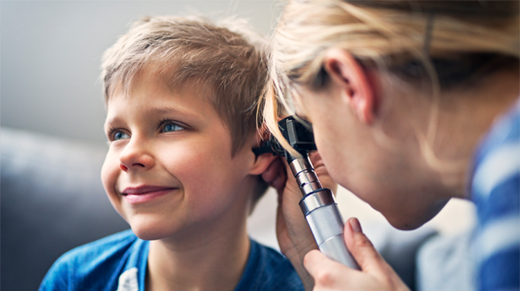 boy receiving ear exam with otoscope.